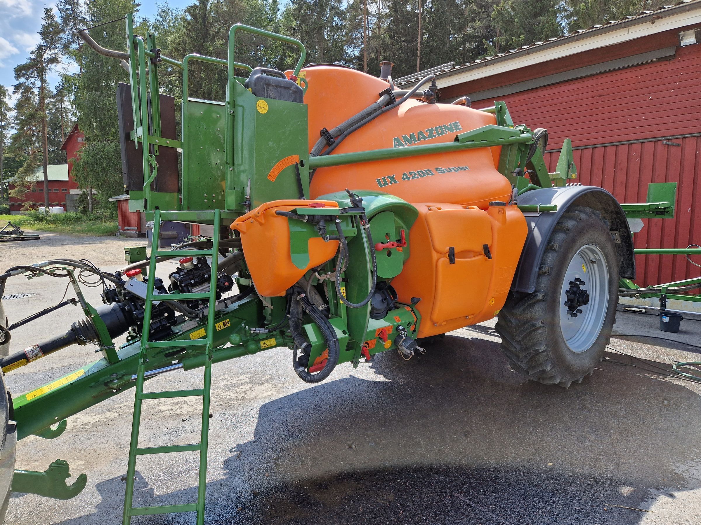 Oranssinvihreä kasvinsuojeluruisku maatilan pihalla.