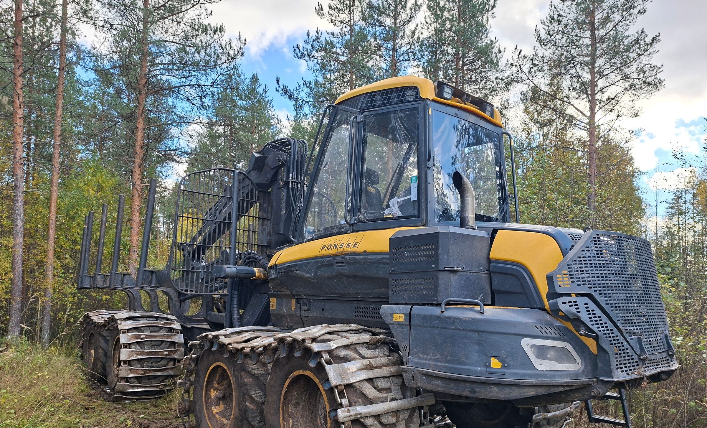 Keltainen ajokone metsässä.